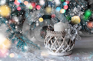 Large white candle in a wicker holder under a Christmas tree. Christmas holiday design. decorated with garlands and glittering