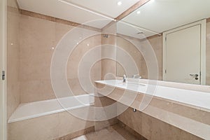 Large white clean bathtub for bathing and daily showering, a wall with a full-length mirror and a marble-topped