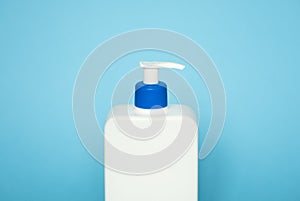 Large white cosmetic plastic bottle with pump dispenser pump and blue cap on blue background. Liquid container for gel