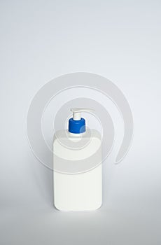Large white cosmetic plastic bottle with pump dispenser pump and blue cap on white background. Liquid container for gel