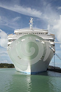 Large white cruise ship docked in the port with looking directly towards the ships bow, Caribbean