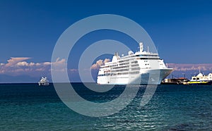 A large white cruise ship stands at the pier in the tourist port at sunset