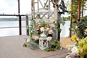 Large white decorative candle lantern, flowers, autumn leaves and old vintage doors on outdoor terrace. Wedding decor, event