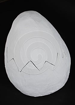 A large white egg made of papier-mache. Decor. On a black background.