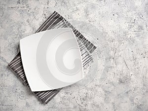 A large white empty plate lies on a decorative towel on an abstract background