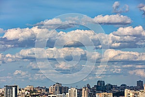 Large white and gray clouds float in the blue sky over the city