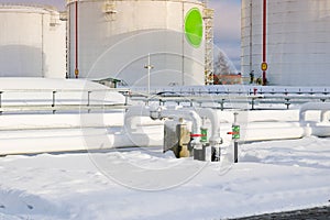 Large white iron metal industrial tanks for storage of fuel, gasoline and diesel and pipeline with valves and flanges