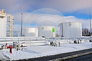 Large white iron metal industrial tanks for storage of fuel, gasoline and diesel and pipeline with valves and flanges