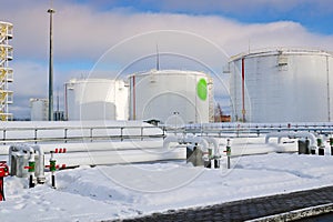 Large white iron metal industrial tanks for storage of fuel, gasoline and diesel and pipeline with valves and flanges