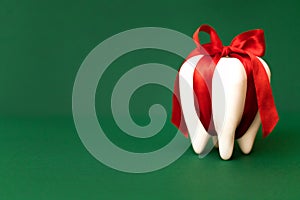 Large white modal molar is tied with a red ribbon with a bow