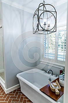Large white renovated master bathroom bathtub with red brick floors