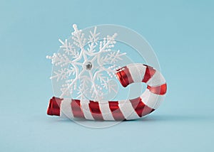 A large white snowflake on a sledge made of New Year\'s red and white ornaments sticks. Minimal Christmas concept on blue