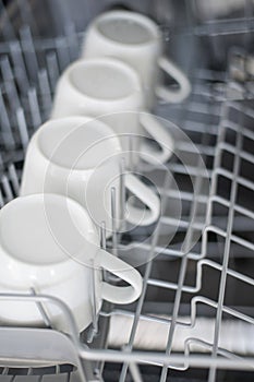 Large white tea mugs are stacked in the dishwasher