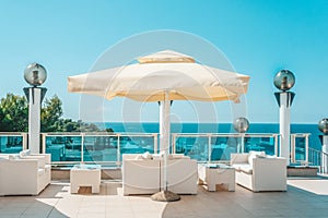 Large white umbrella and outdoor furniture sofas and rattan chairs with cushions and a glass-topped table. Place to relax on the
