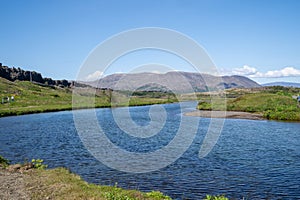 Large wide river through Thingvellir National Park in Iceland on a sunny day