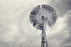 A large wind turbine in the blue sky on a cloudy day.