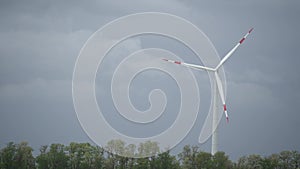 Large wind turbines with blades in field bright orange sunset blue sky wind park slow motion drone turn. Silhouettes