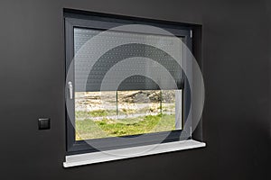 A large window in a room with black walls, half covered with external blinds. photo