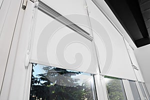 Large window with white roller blinds indoors, low angle view