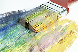 A large wooden art brush paints on canvas. Drawing technique. Bright colors on the canvas. Hobbies and creativity.