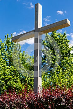 A large wooden crucifix in the city park. Place of religious worship. Catholic faith. A cross under a blue sky against a backgroun