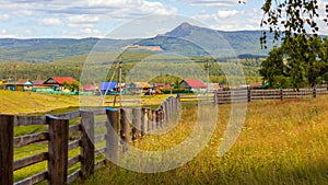 a large wooden fence on a private plot in the village of Shigaevo in the Southern Urals against the backdrop of mountains and Arvy