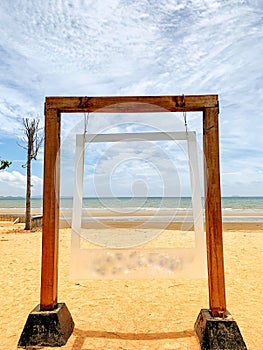 Large wooden picture frame on a sandy beach background, background, landscape, sea and beautiful sky.  Holiday Concept
