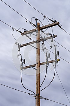 A large wooden power pole with transmission lines and communication cables