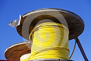 Large wooden rolls with yellow wires wrapped around