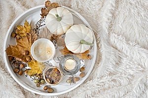 Large wooden serving with a Cup of coffee with brown sugar, burning candles .Seasonal decoration of foliage and pumpkins