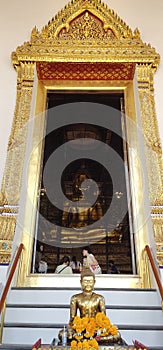 A large yellow Buddha sits in a church for worshipers to take photos from outside.