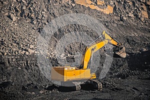 Large yellow excavator with full bucket of black coal will carry out loading in open mine