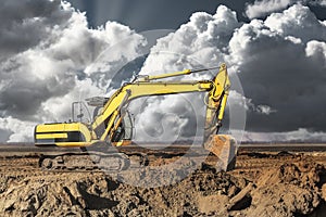 A large yellow excavator moving stone or soil in a quarry. Heavy construction hydraulic equipment. Excavation