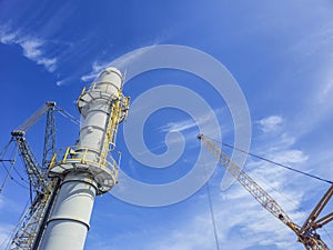 A large yellow and gray crane is lifting a large gray and yellow structure