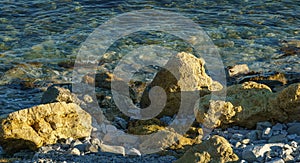 Large yellow rocks against the backdrop of the blue sea at sunset. Sea stones and rocks of different sizes and texture on beach