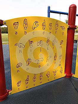 Yellow sign language alphabet guide board on children`s playground photo