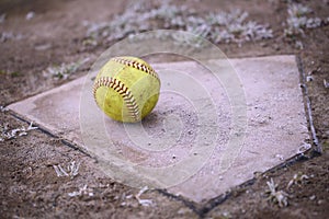 A large, yellow softball rests on home plate.