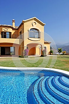 Large yellow sunny spanish villa with pool and blue sky