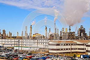 The largest Canadian oil refinery in the background, parking in the foreground, smoking pipes