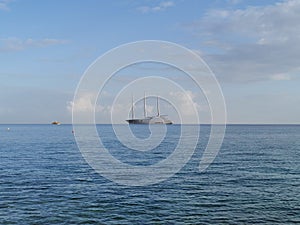 The largest sailing yacht in the world, an eight-deck motorsailer on the Mediterranean coast against a blue sky with clouds