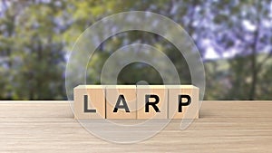 Larp word wooden cubes on table vertical over blur background with trees green sky, mock up, template, banner with copy space for