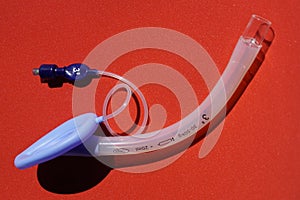 Laryngeal mask airway for emergency medical help on a red background.