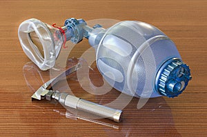 Laryngoscope and Ambu Bag for ventilation resuscitation on wooden table, 3D rendering