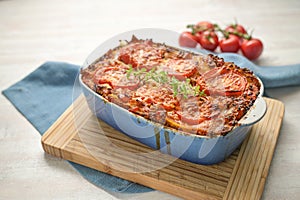 Lasagna, fresh from the oven, casserole dish of flat pasta sheets, ground beef sauce, vegetables and tomatoes, topped with melted