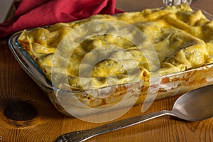 Lasagne in baking dish with serving spoon on kitchen table