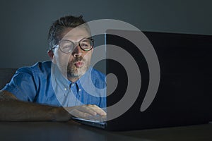 Lascivious aroused addict man in nerd glasses watching sex movie online late night at laptop computer looking pervert and