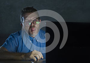 Lascivious aroused addict man in nerd glasses watching sex movie online late night at laptop computer looking pervert and