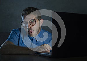 Lascivious aroused addict man in nerd glasses watching sex movie online late night at laptop computer looking pervert and photo