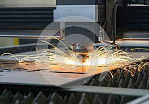 Laser cutting machine creating sparks while processing metal sheet