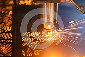 Laser cutting machine working with sheet metal with sparks in dark: close up